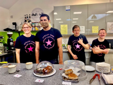 A group of people standing in a kitchen with food on the tableDescription automatically generated with low confidence